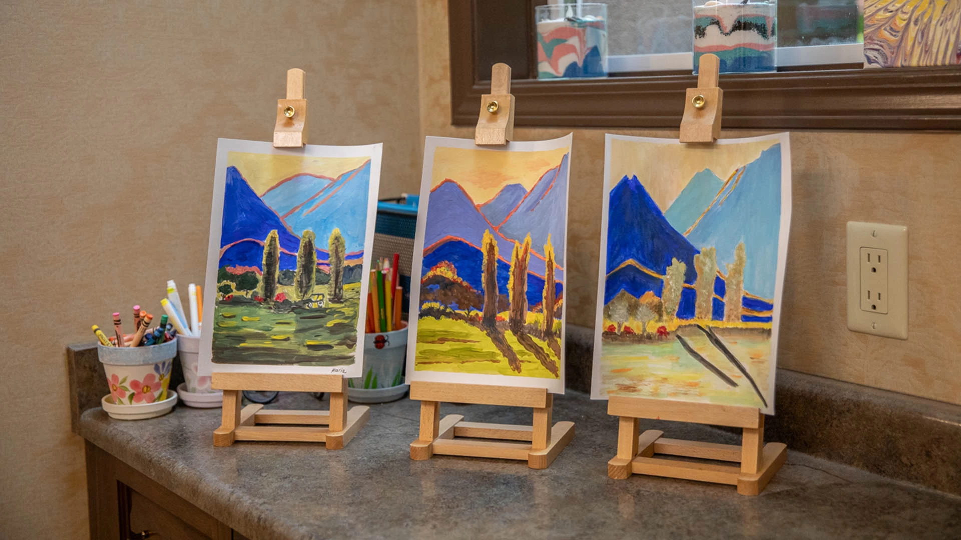 3 paintings being displayed on a counter top