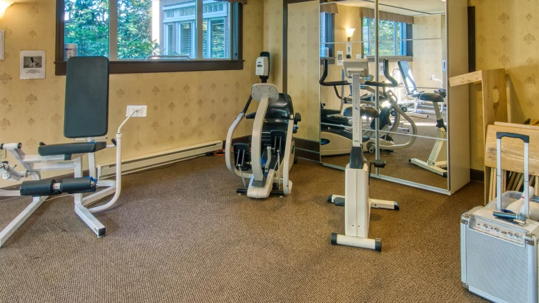 A gym room with a variety of exercise equipment.