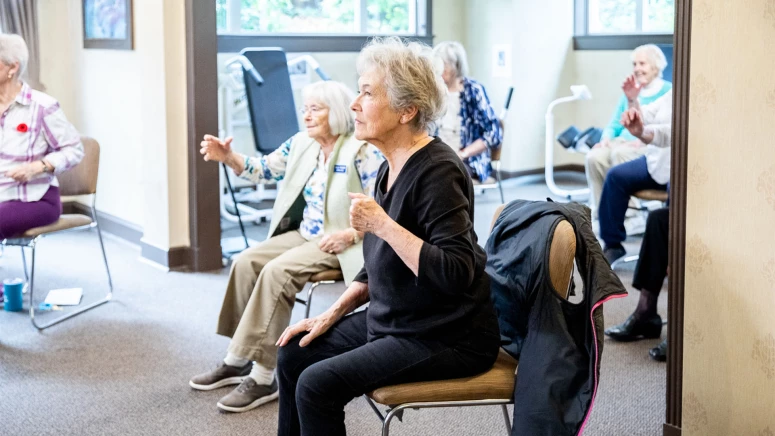 A group of older women are exercising in chairs in a room.