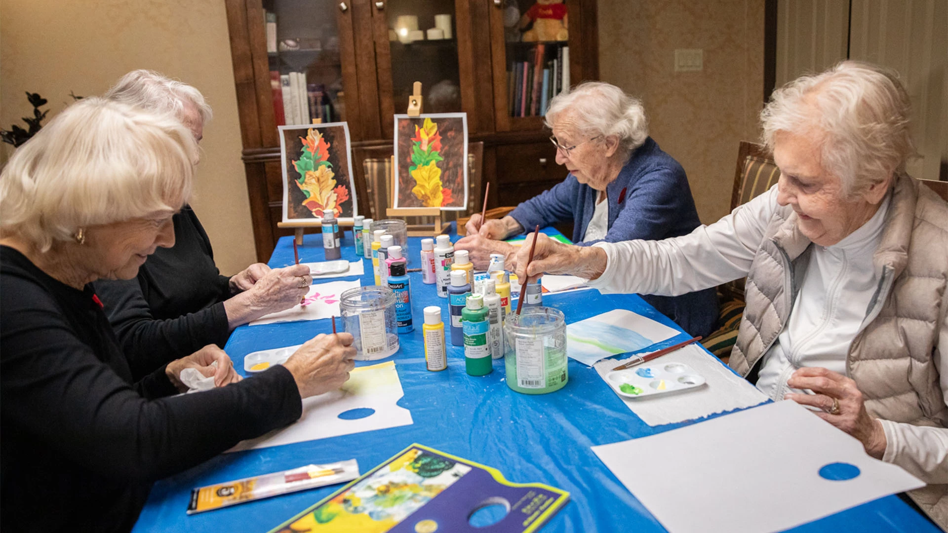 A group of older women painting at a table.